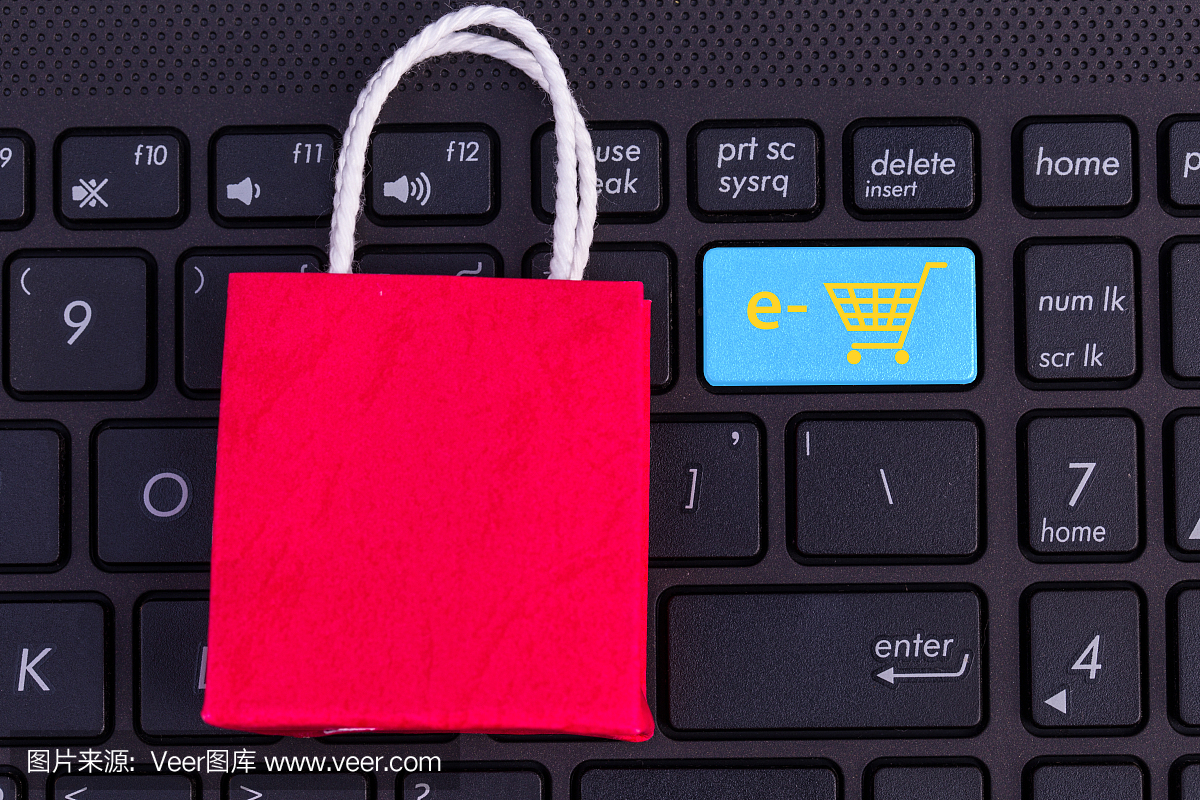 笔记本电脑键盘上的红色纸购物袋。关于网上购