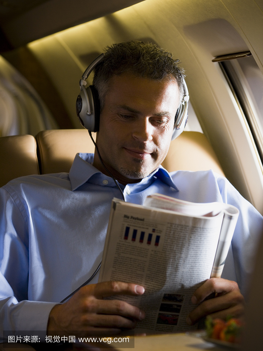 在飞机上读一本杂志的老人