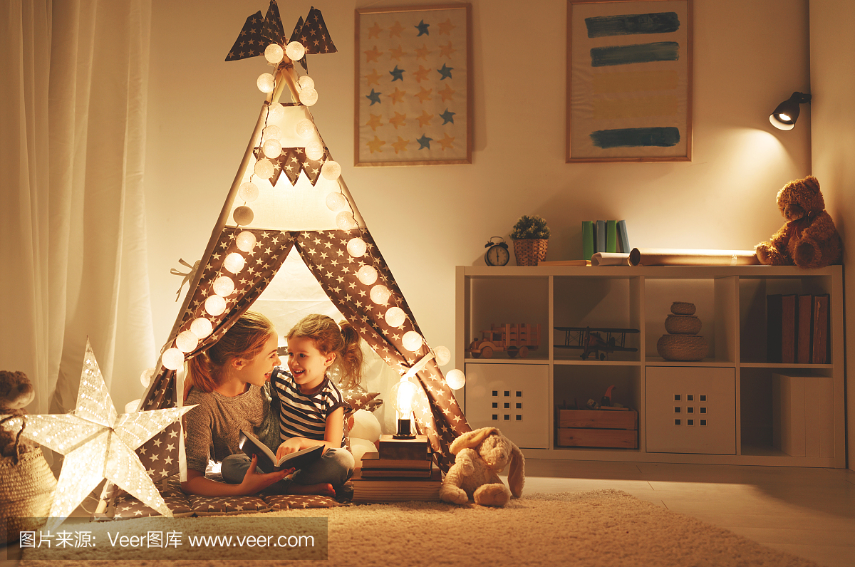 母亲和孩子的女儿在睡觉前读一本书和一个手电