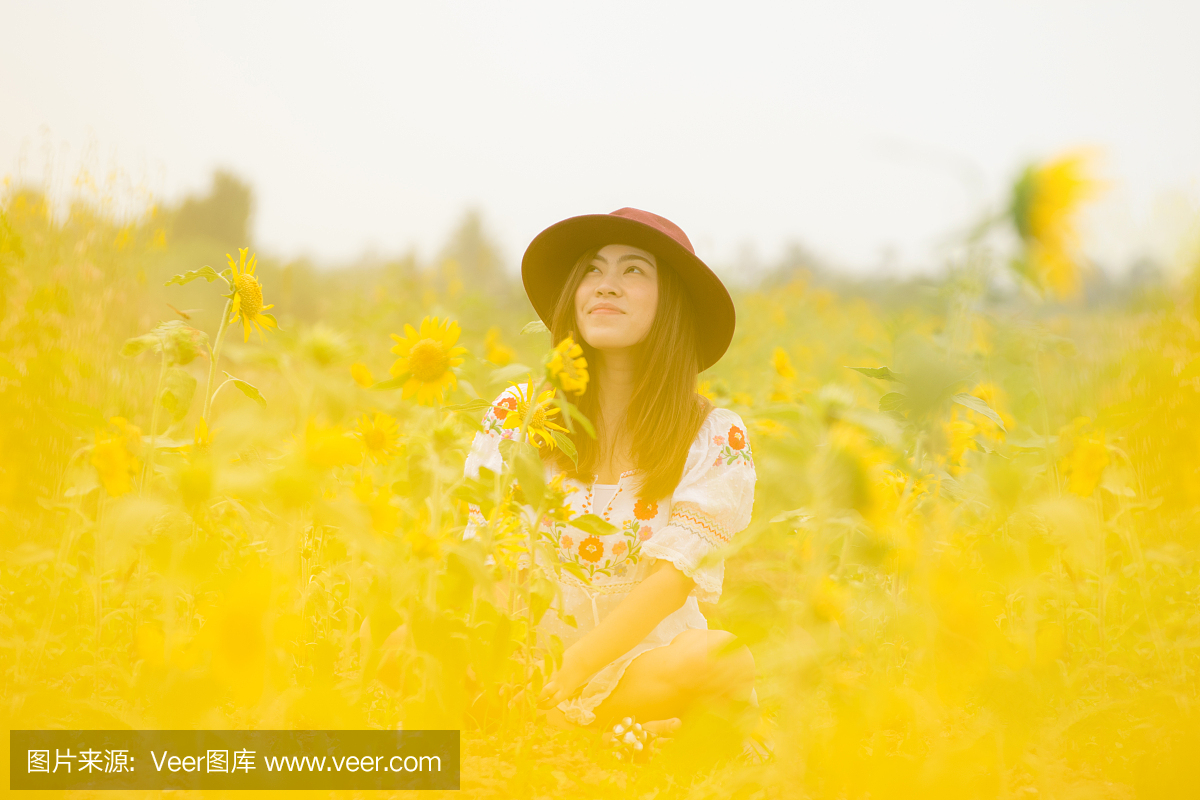 美丽的亚洲女人喜欢旅游到向日葵田。