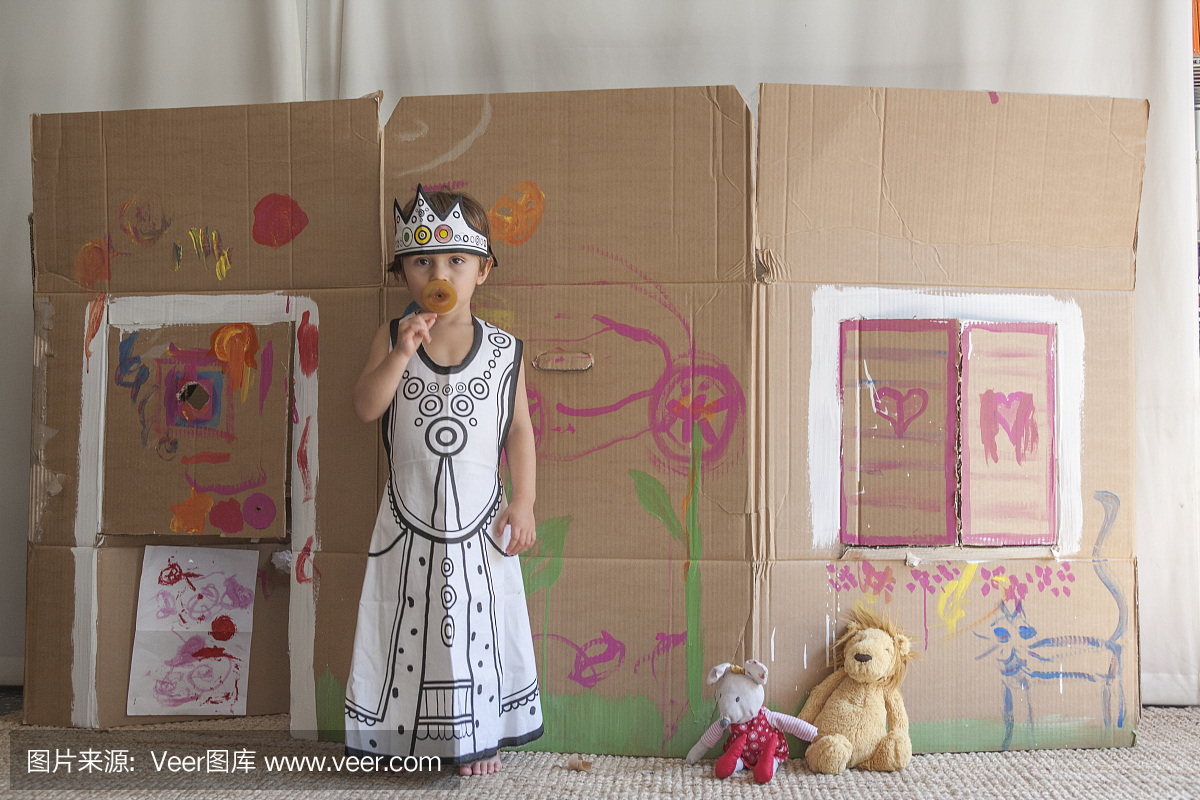 一个小女孩在一个彩绘纸房子前打扮成女王