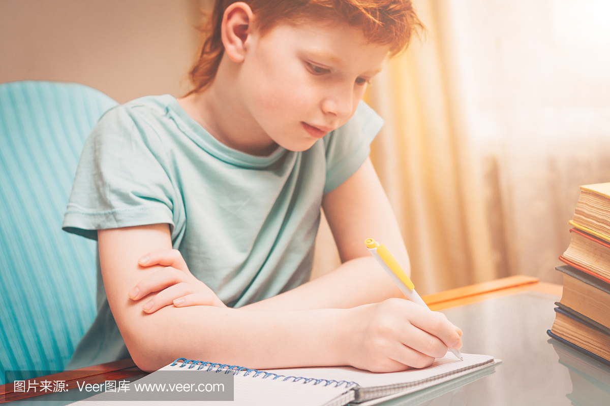 红头发的男孩在做笔记本的同时做书包围的家庭