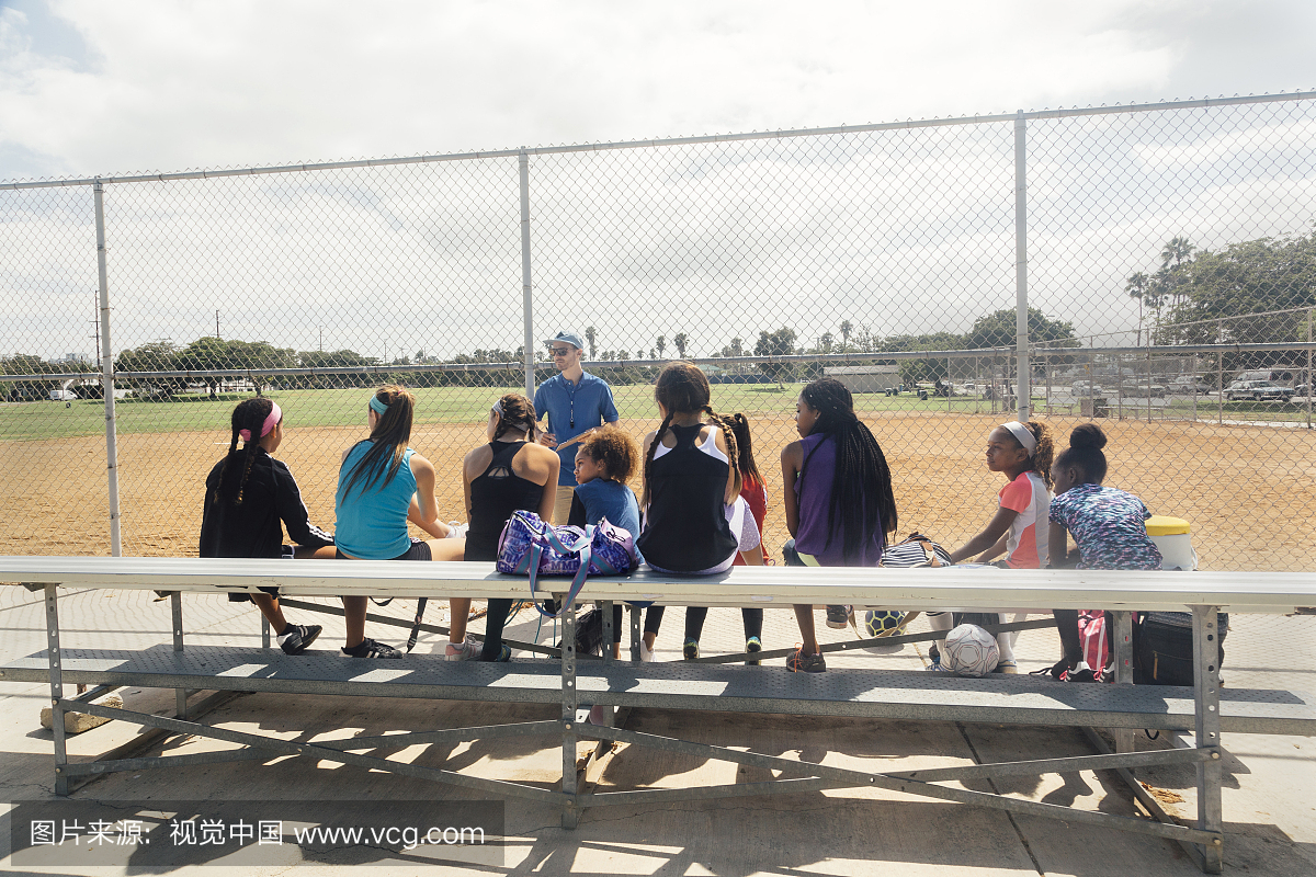 指导女学生足球运动员在学校体育领域长凳上的