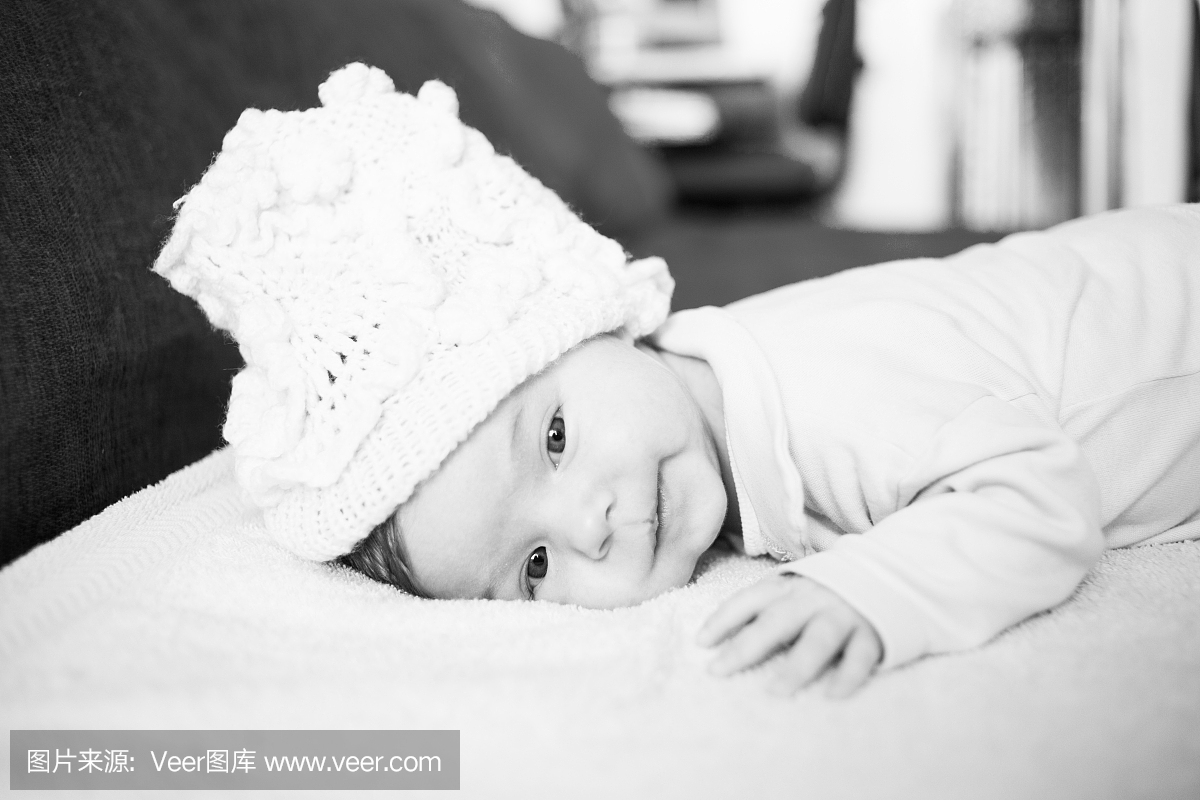 可爱的3个月宝宝,戴帽子躺在毯子上