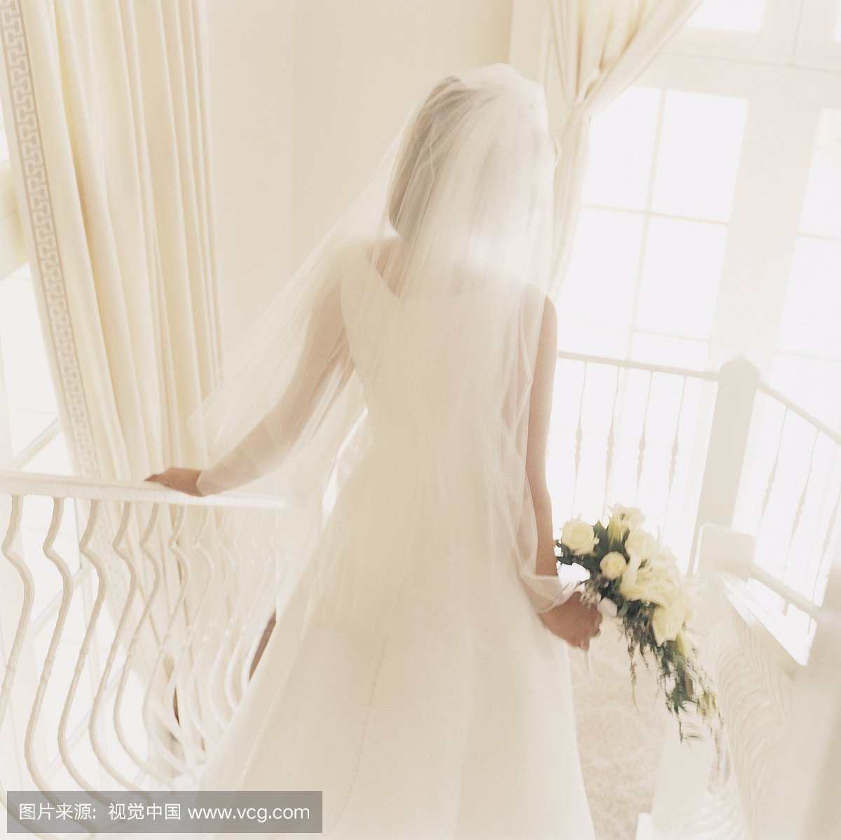 婚纱礼服的新娘后视图降序白色的楼梯