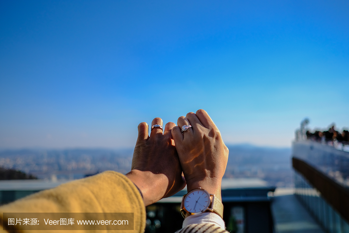 两只手与天空背景上美丽的结婚戒指(选择性焦