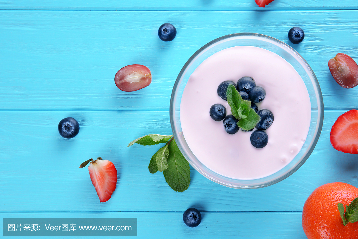 与美味的自制酸奶和成分在蓝色背景上的组成