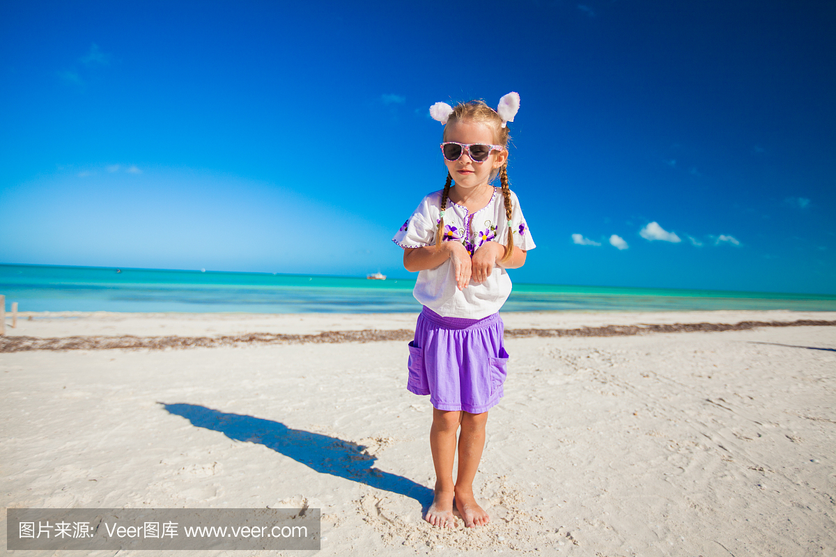 可爱的小女孩在异国情调的海滩上的复活节服装