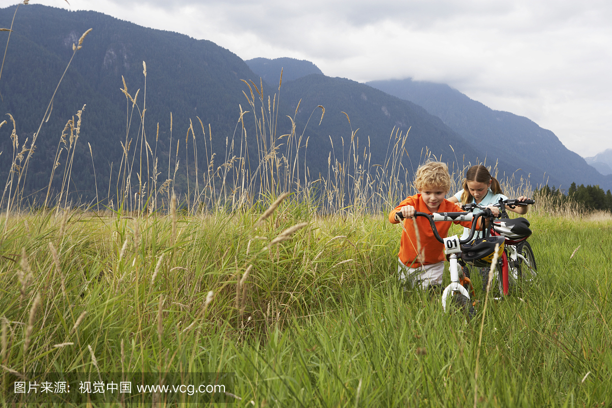 男孩和女孩(5-8岁)通过长草推山地自行车