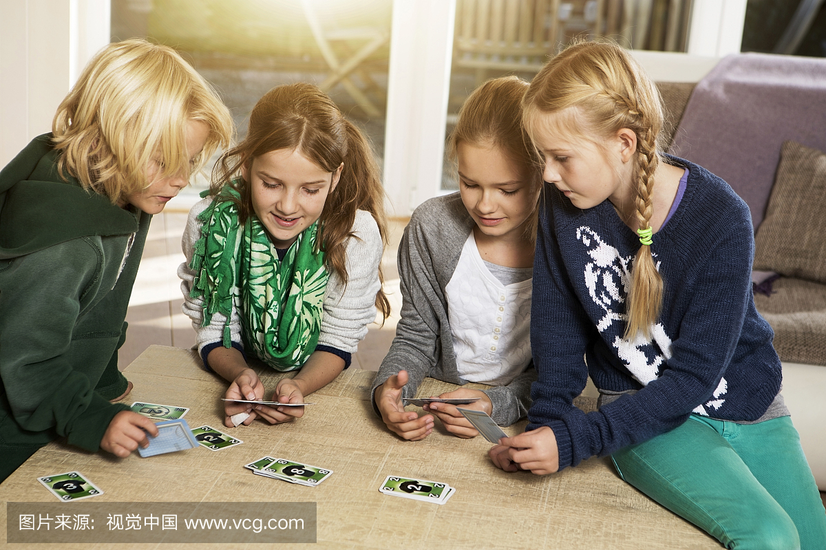 四个孩子在客厅玩纸牌游戏