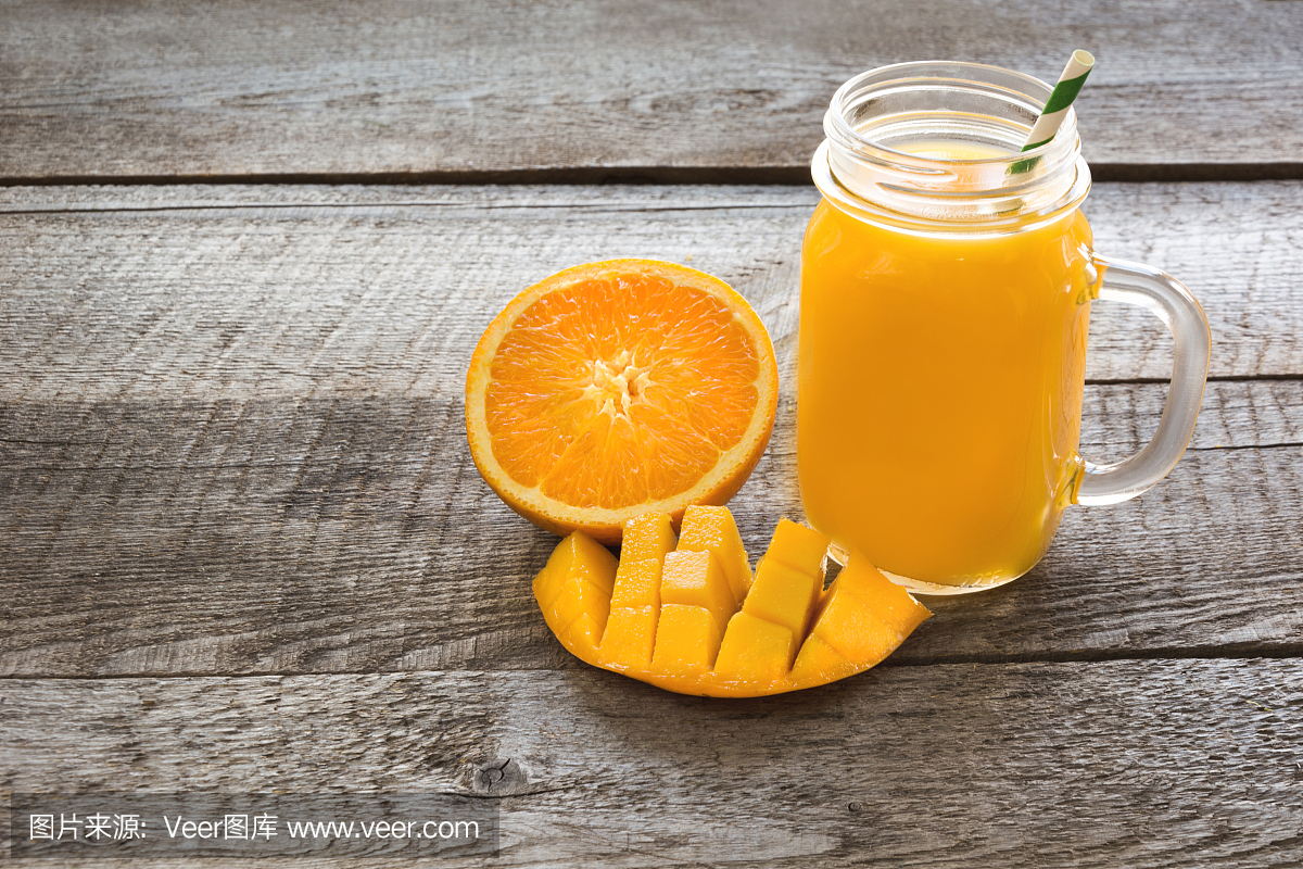 热带果汁芒果,橙子,香蕉水果在罐中与秸秆在木