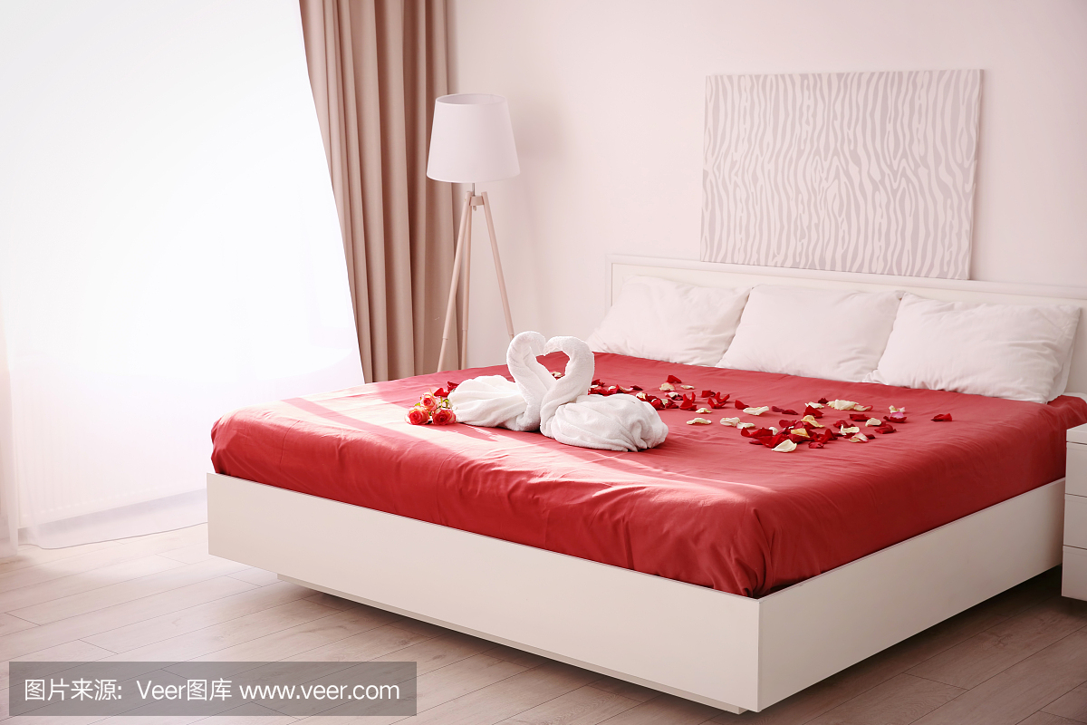 两间毛巾天鹅和玫瑰花瓣在旅馆房间的床上