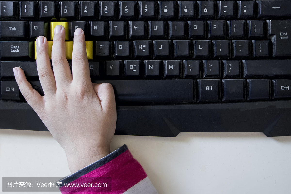 一个小孩的手与电脑键盘。小亚洲男孩使用计算