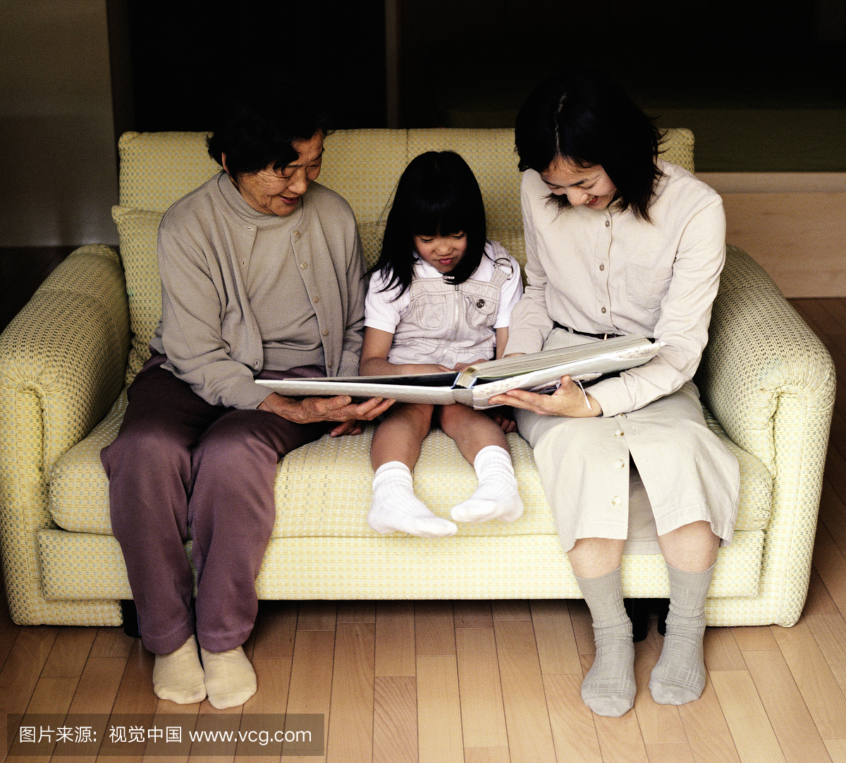 祖母,母亲和女儿(6-8)在沙发上看相册