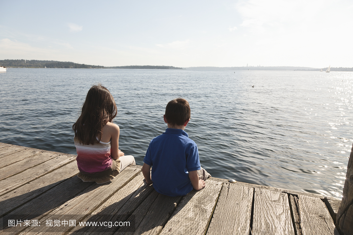 坐在码头边缘的男孩(5岁)和女孩(8岁)看过美国