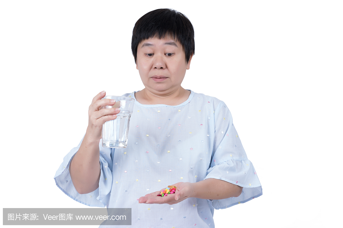 亚洲中年妇女拿着杯水和看很多药片,她必须采