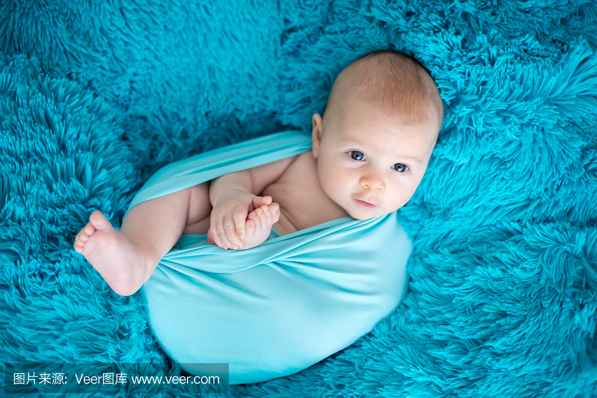 可爱的三个月大男婴在蓝色的包裹,躺在蓝色的
