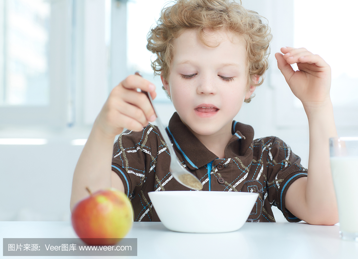 男孩在厨房里吃早餐时吃麦片。