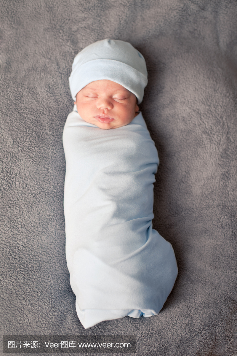 新生婴儿包裹在蓝色的毯子和戴帽子