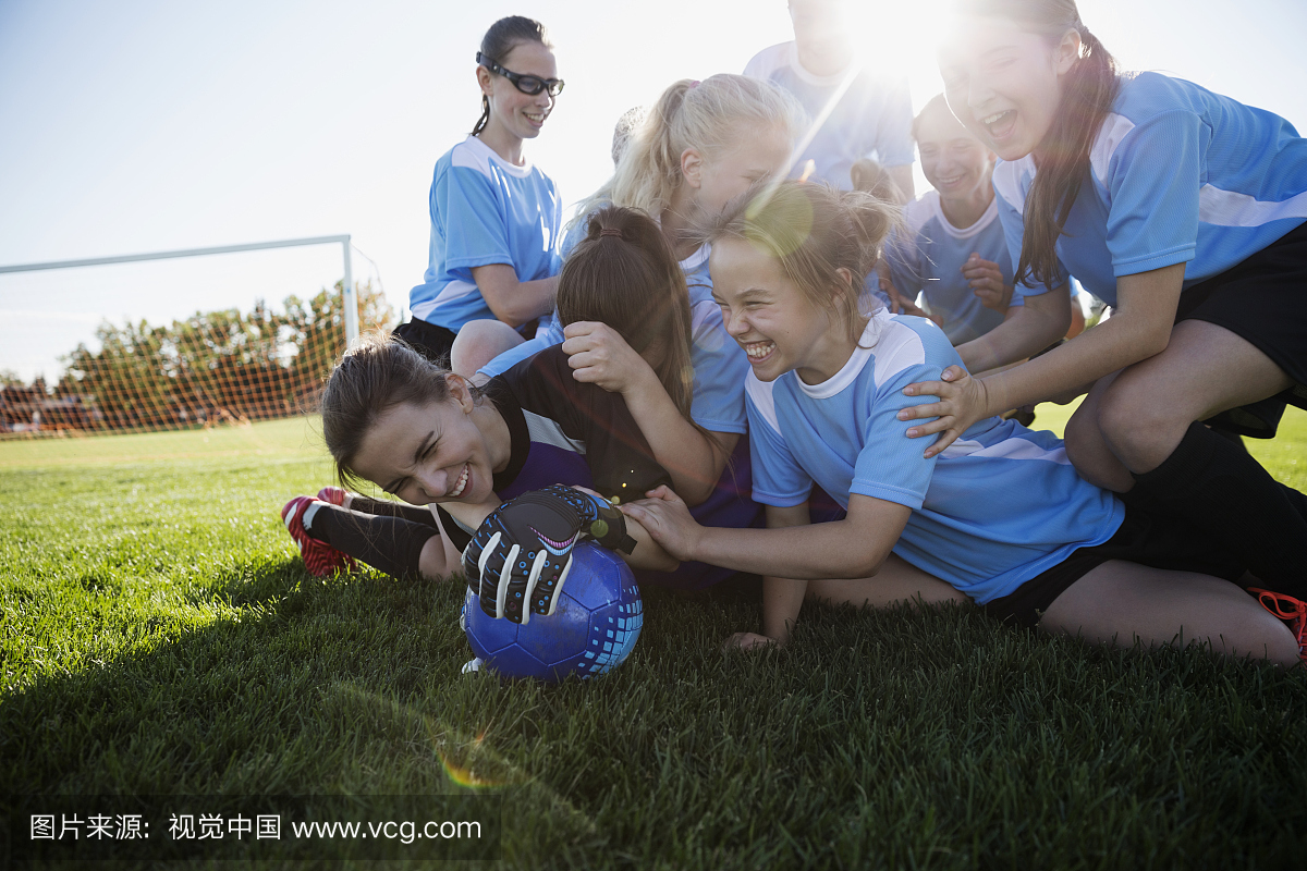 嬉戏的中学女子足球队在阳光明媚的田野上庆祝