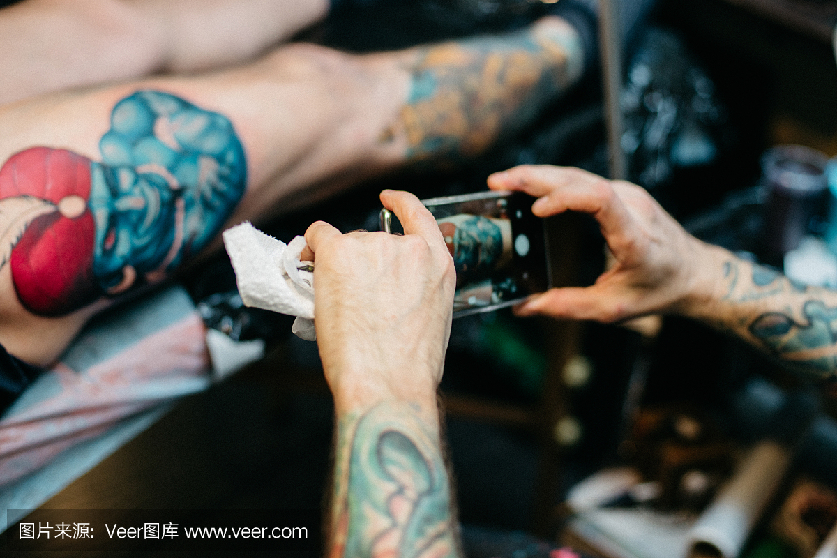纹身艺术家制作他的工作与智能手机的照片