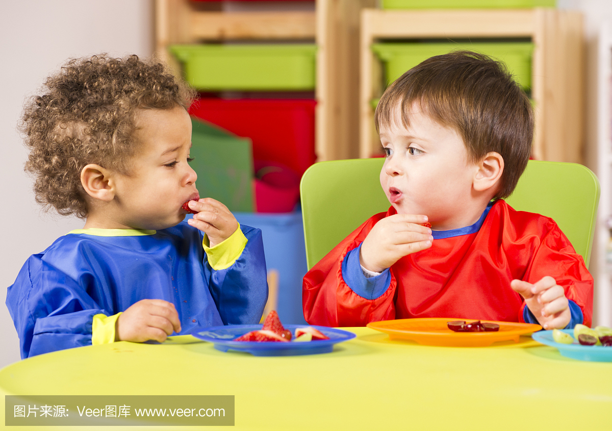 两个在幼儿园吃水果的孩子