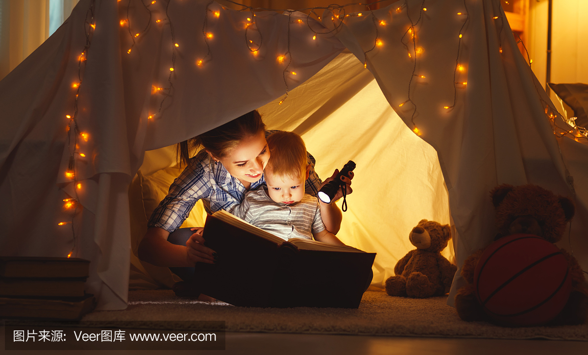 母亲和孩子的女儿在睡觉前带着书和手电筒
