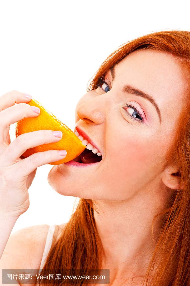 年轻的红头发的女人用橘子在她的手中