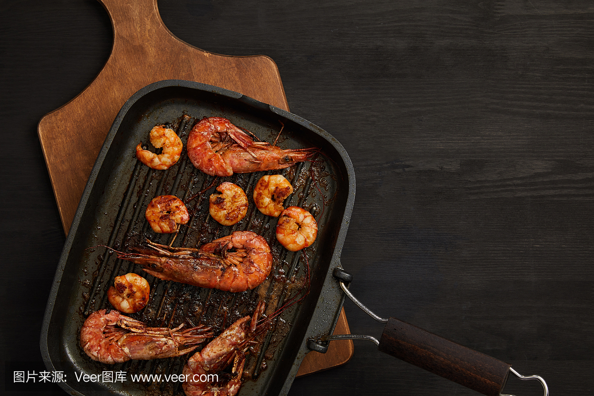 烤虾顶视图在木切板的在黑桌面