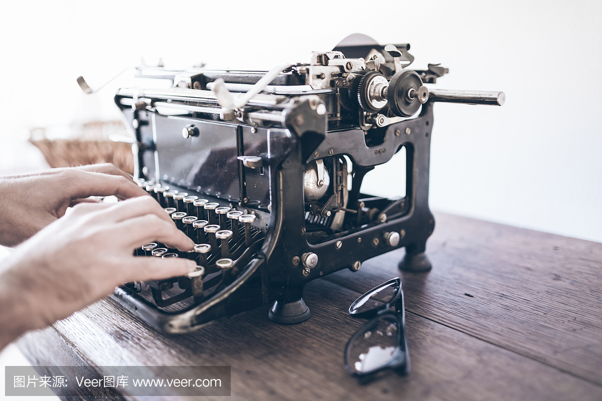 使用老式手动打字机在仿古木制的桌子上的特写