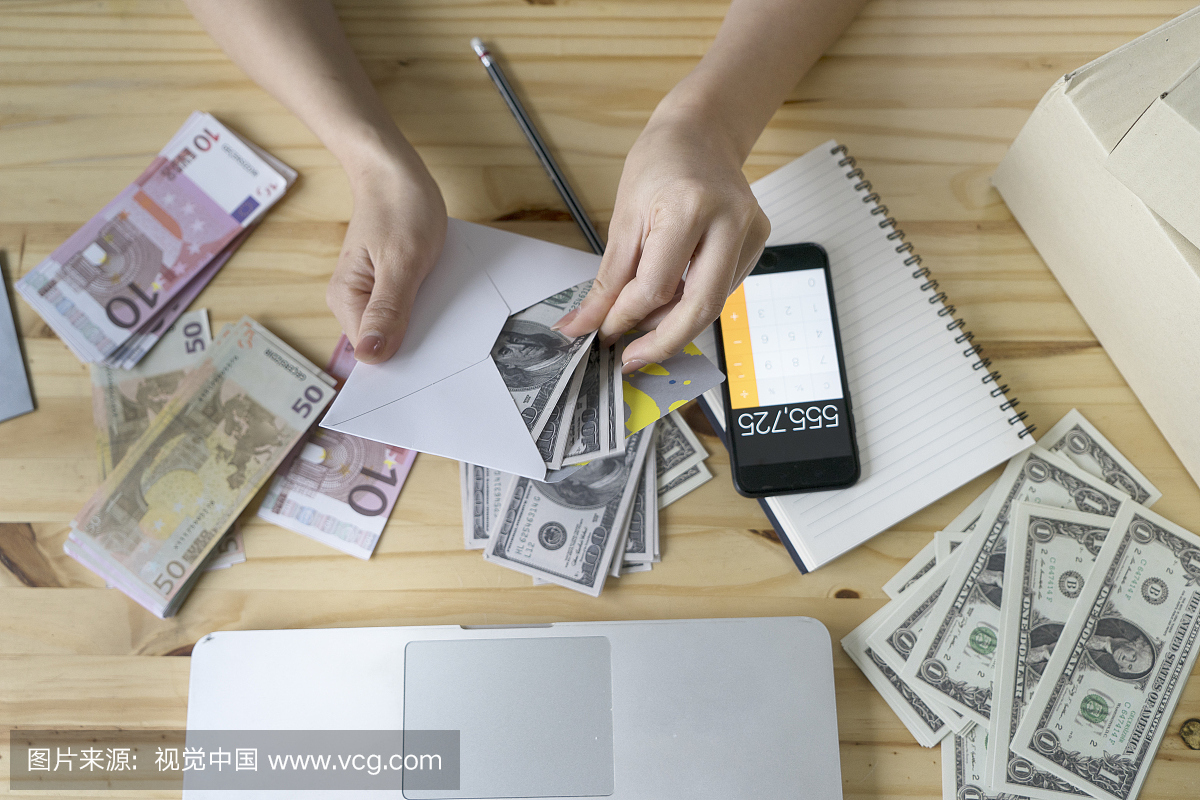 亚洲业务女孩拿着金钱和在房子里使用智能手机