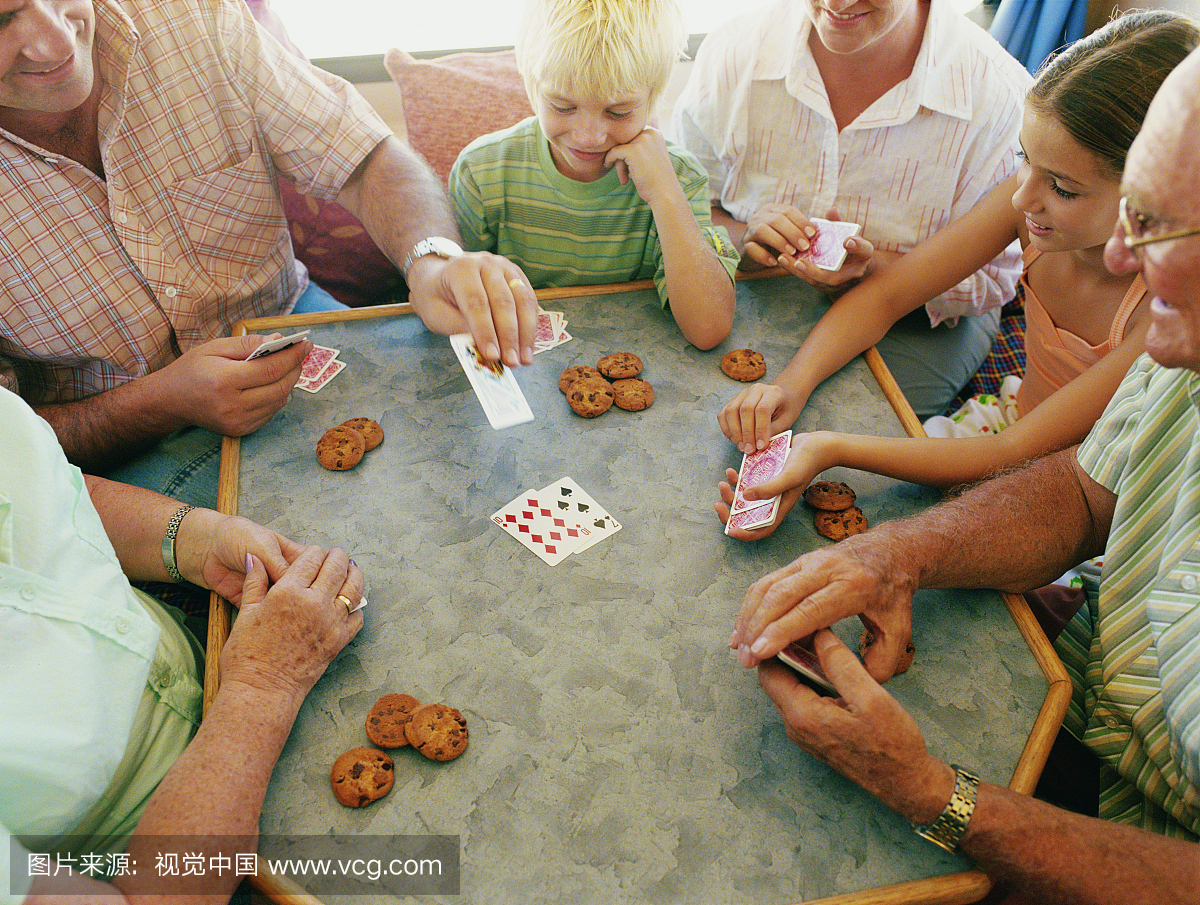 三代家庭聚集在桌上玩纸牌游戏