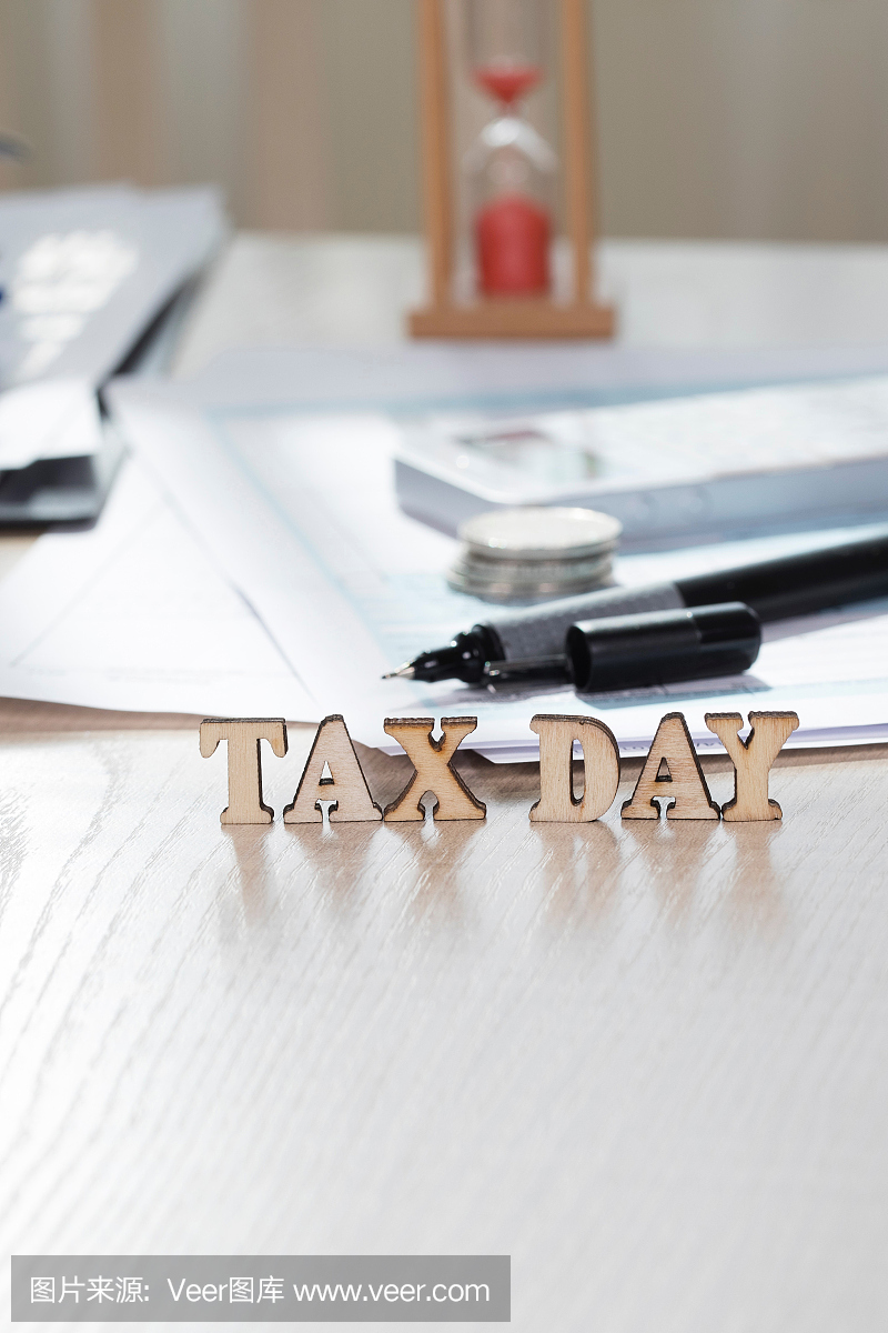 Word Tax Day由木制字母组成。硬币,论文,笔在