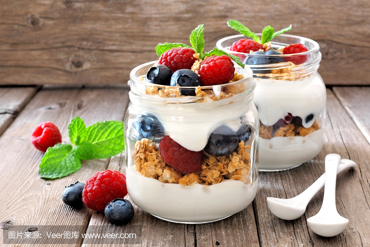 蓝莓,覆盆子在梅森罐头,静物反对木材