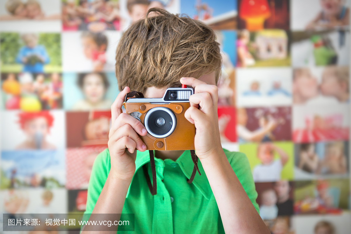 男孩与复古相机在一张照片墙前面