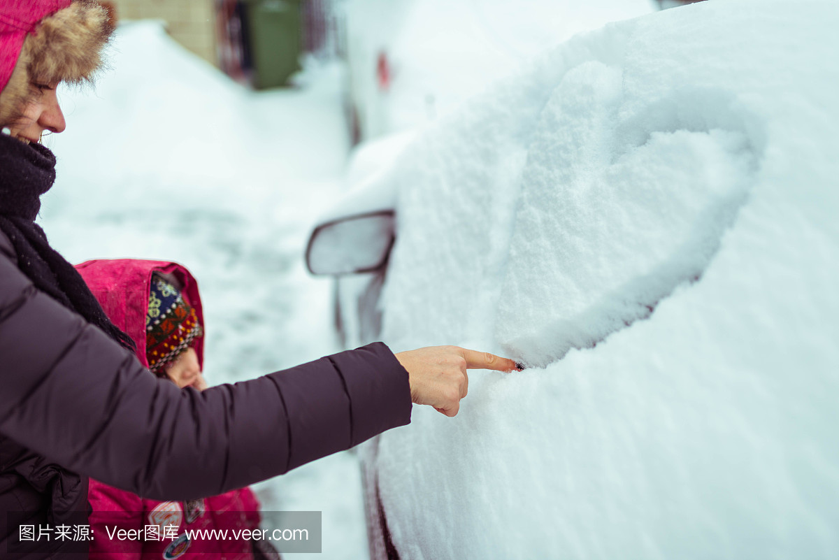 母亲带着女儿在雪地上覆盖着她丈夫的车上画心