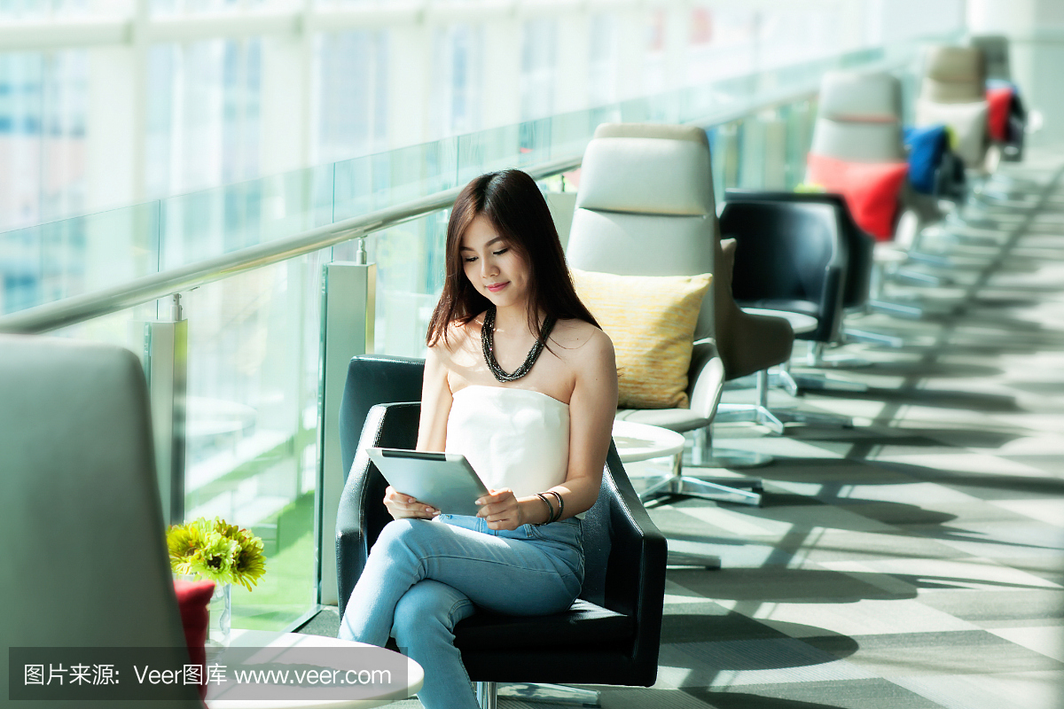 漂亮的女人穿蓝色牛仔裤使用平板电脑