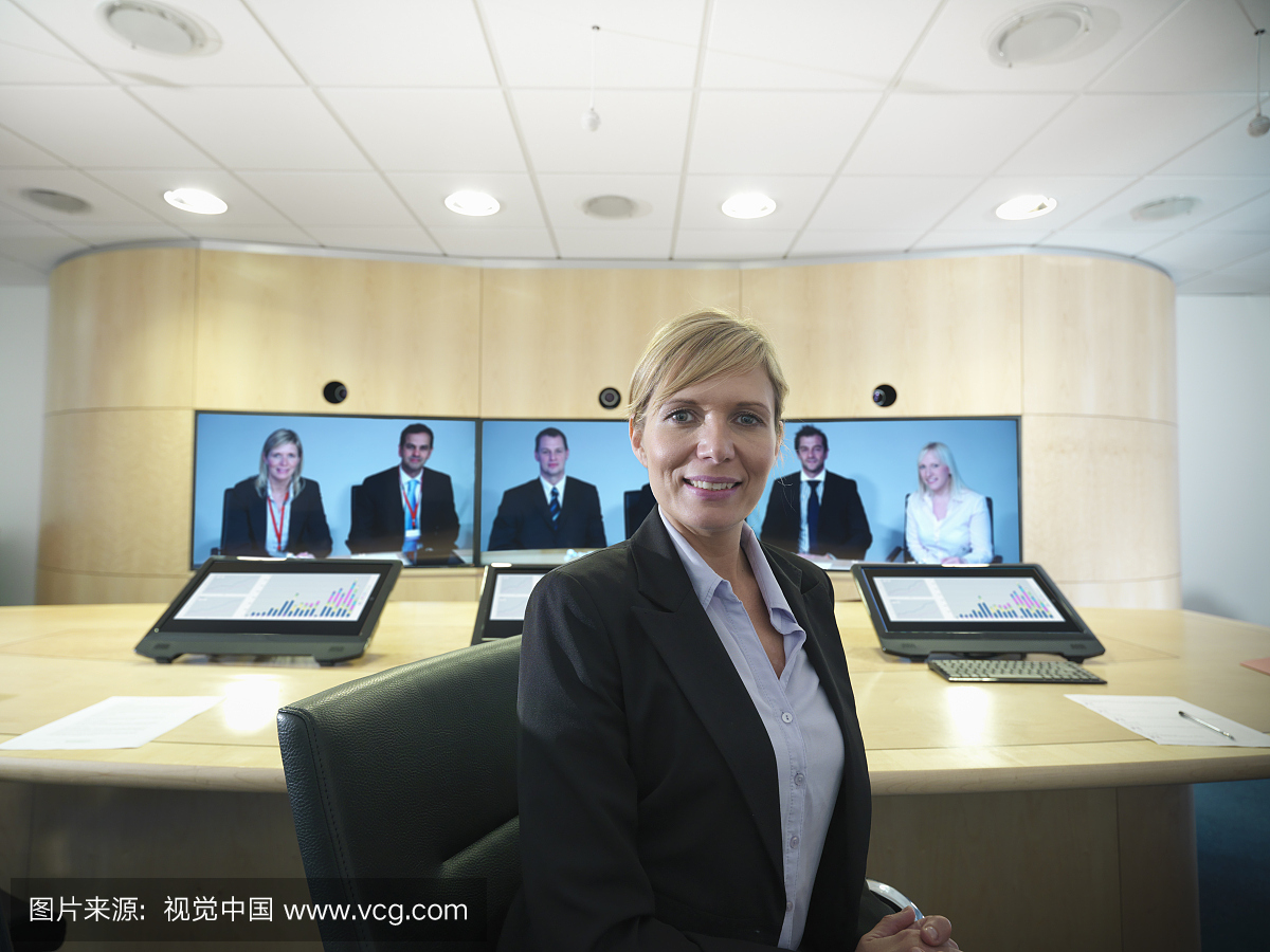 在视频会议屏幕上与同事们坐在会议室的女商人