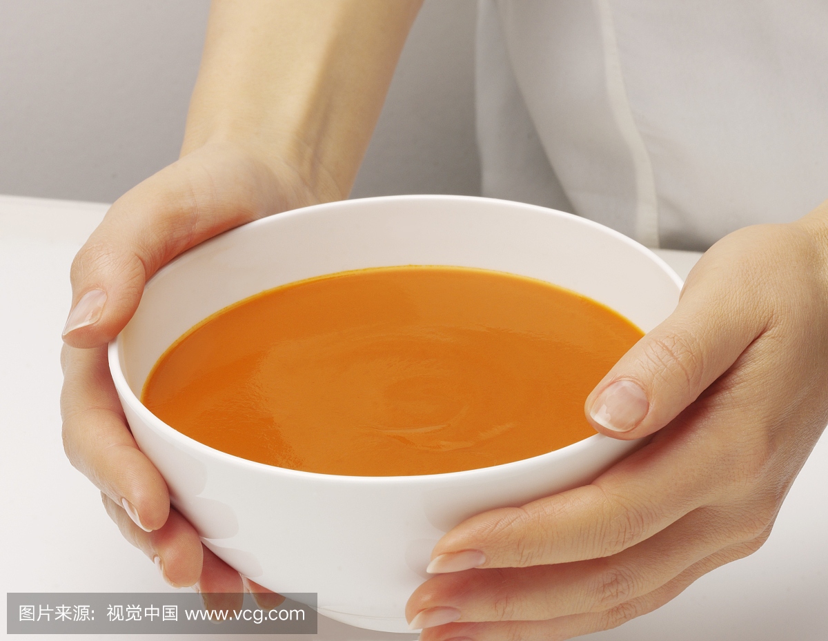 拿着一碗番茄汤的女人的手