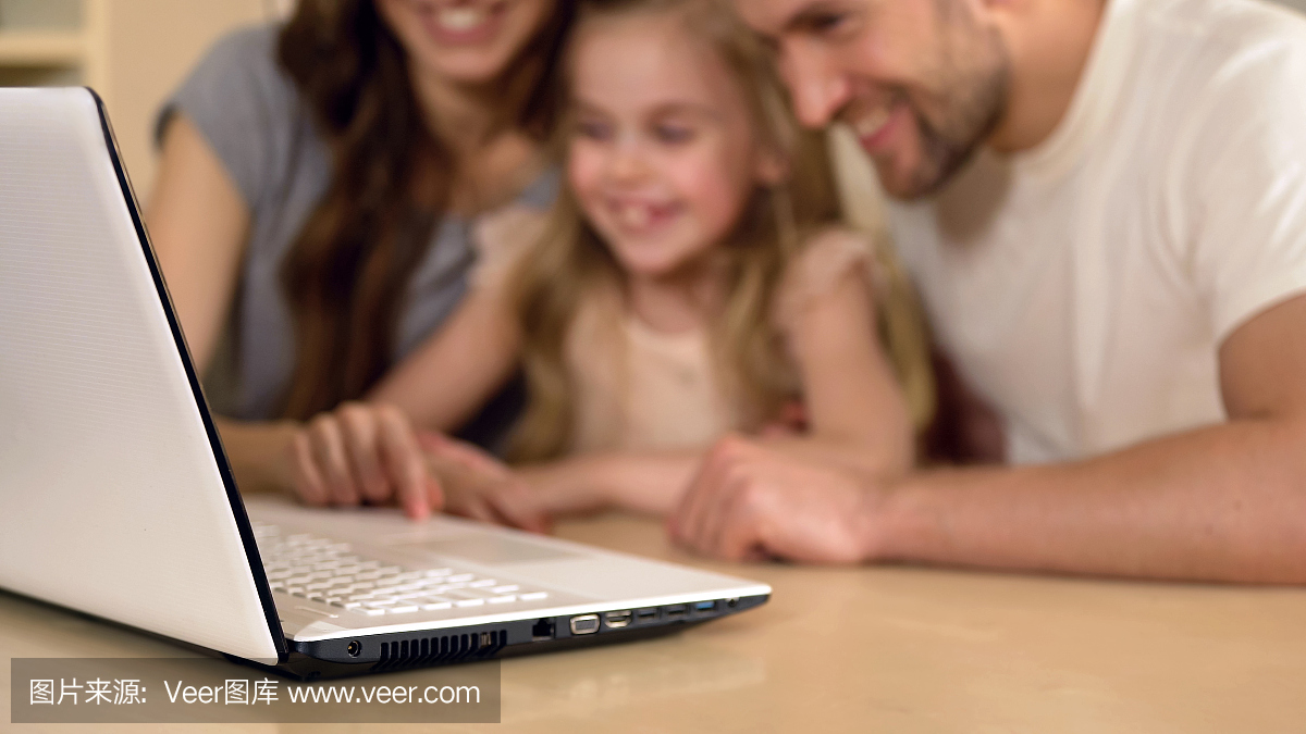 的父母和女儿看着笔记本电脑,享受远程教育的