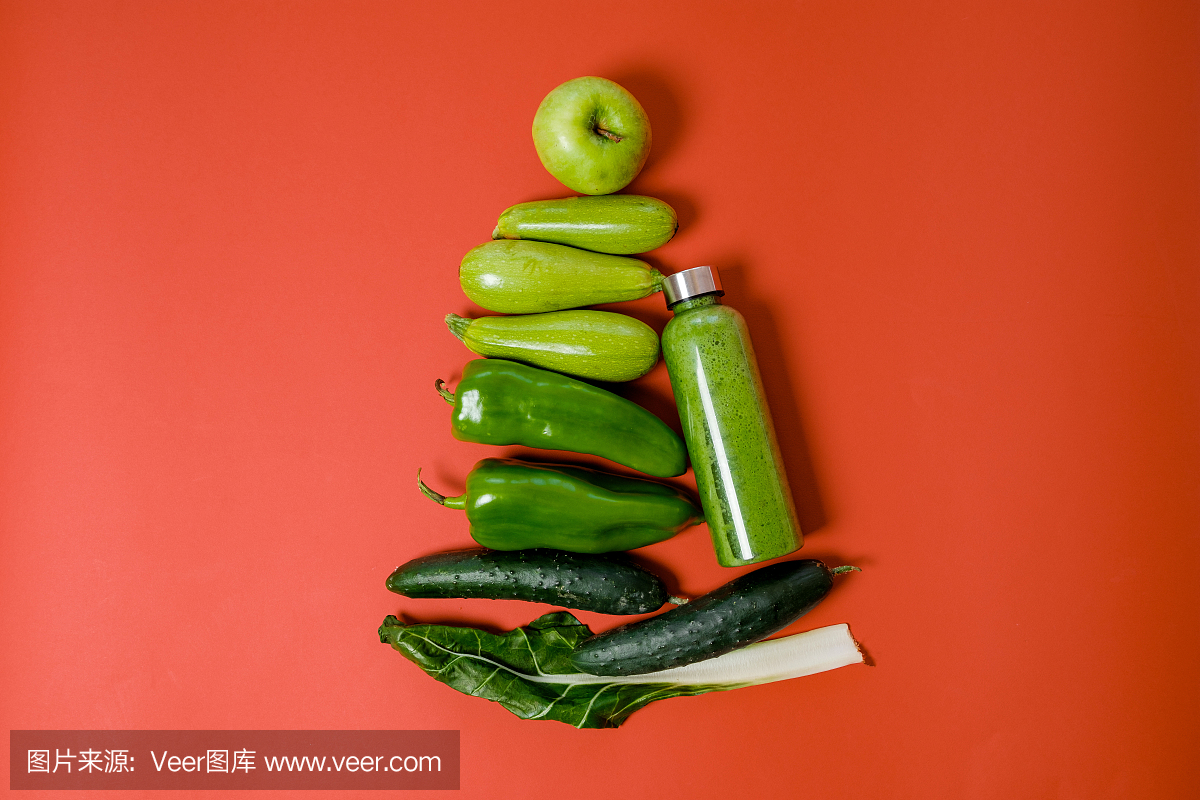 绿色蔬菜和果汁在红色背景上的塑料瓶。健康的