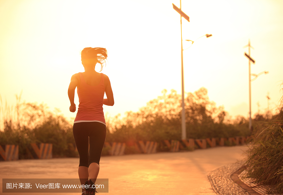 运动女子早晨运动在日出时的山车道上运行