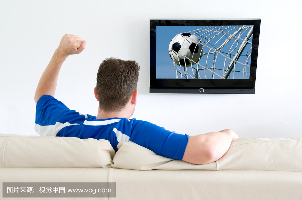 男人从家里看电视上的足球