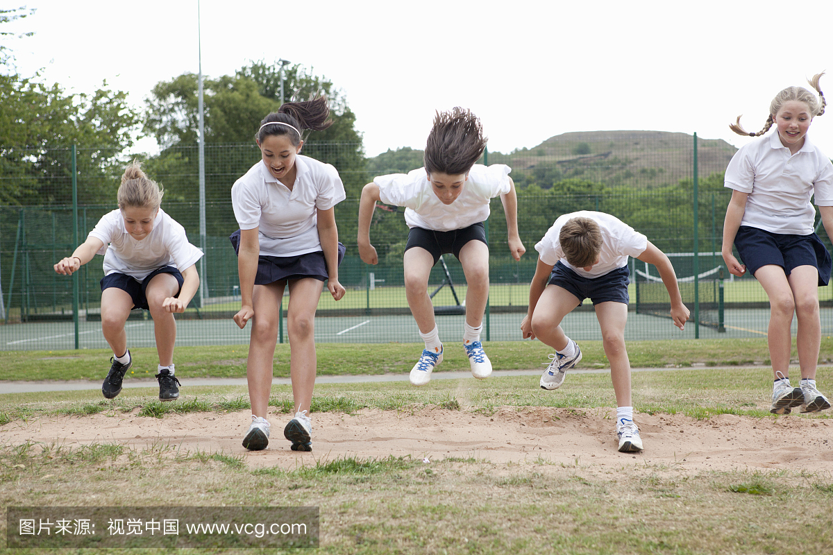 学生在户外的沙坑里跳