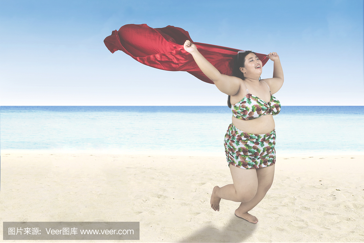 带围巾的肥胖女人在沙滩上跑步