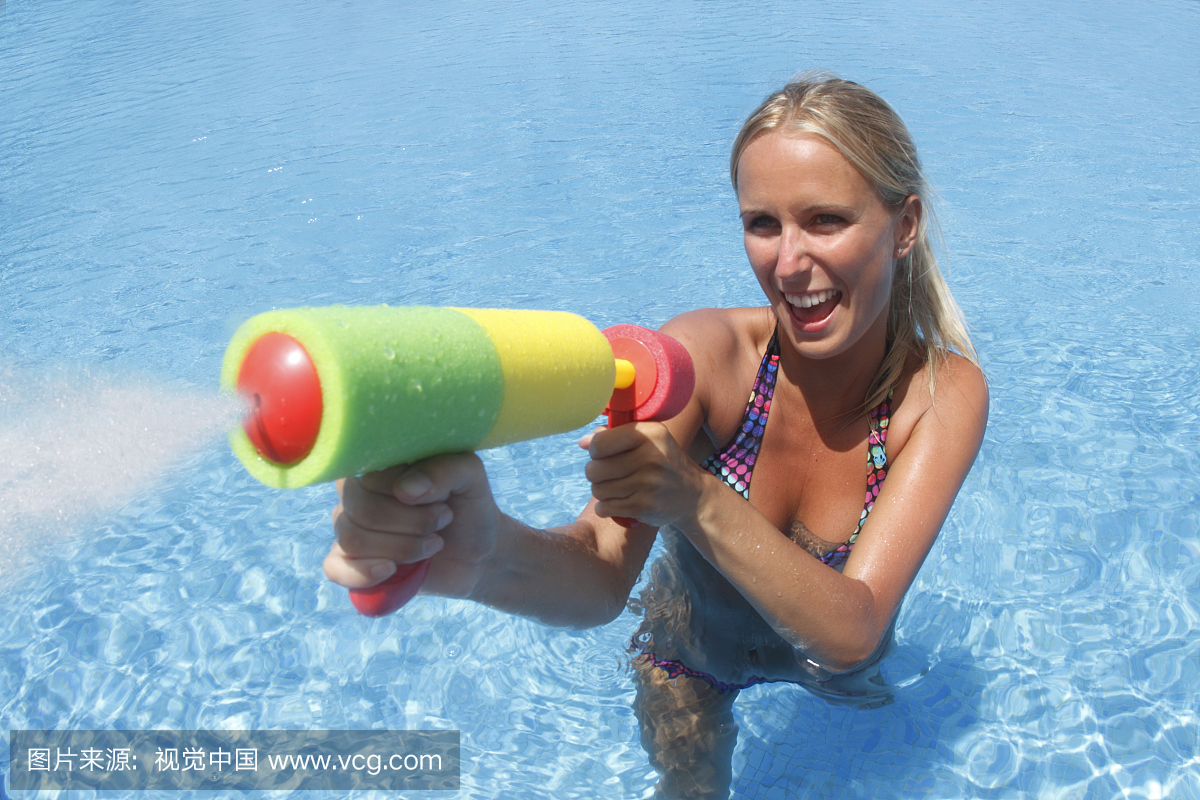 游泳池中的女孩从玩具中喷出水