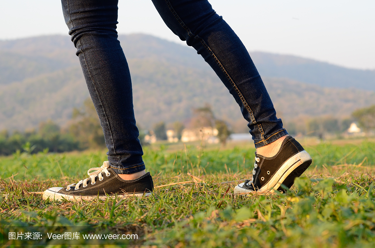 女子穿运动鞋穿过草地与郁郁葱葱的草地
