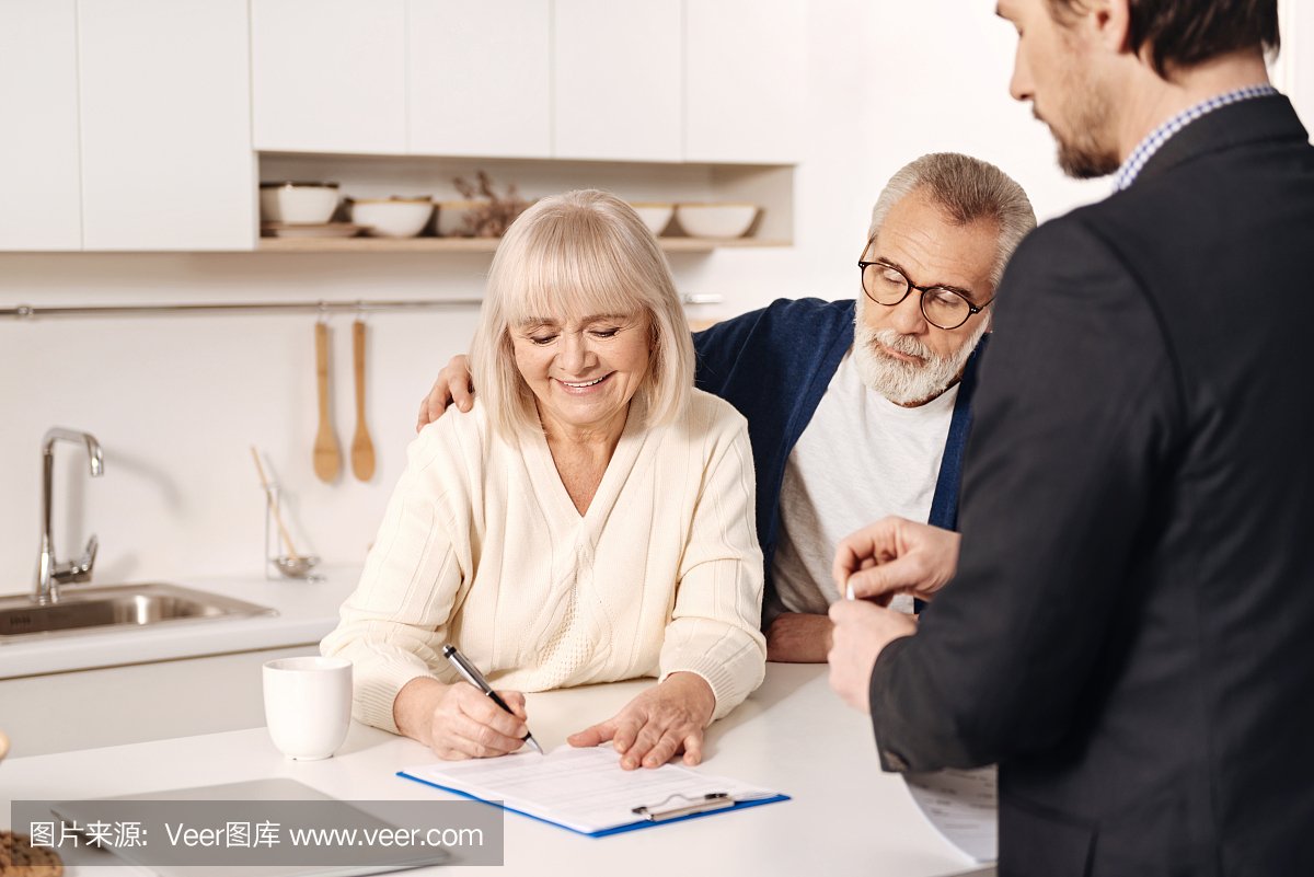 有吸引力的积极老年夫妇在家签署文件
