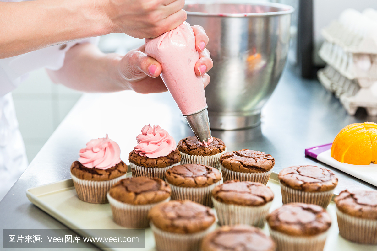 妇女在糕点面包店作为糖果上釉与结冰袋松饼