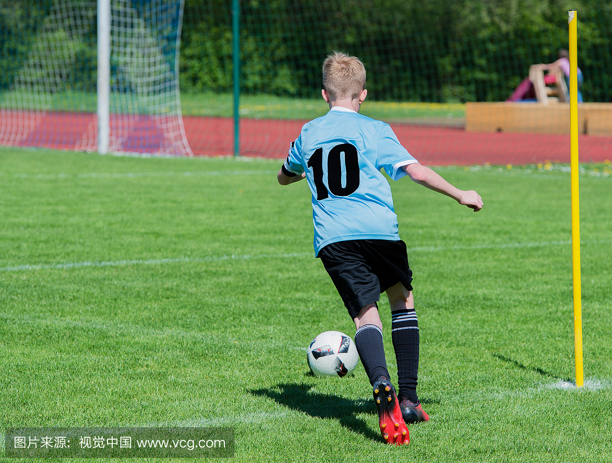 踢足球的男孩背面图在象草的领域